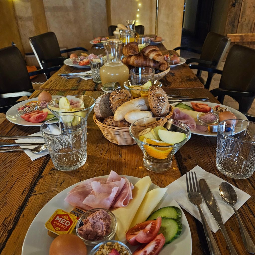 Detailní záběr na cateringové pohoštění na masivním dřevěném stole připravené pro soukromou oslavu či firemní brunch.