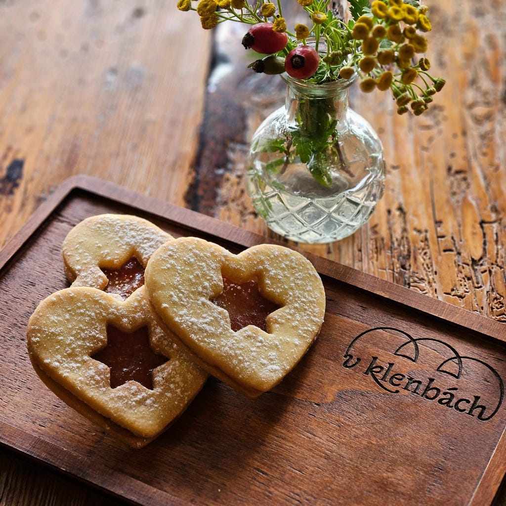 Tradiční linecké cukroví ve tvaru srdce s ovocným džemem na dřevěném prkénku s logem kavárny.