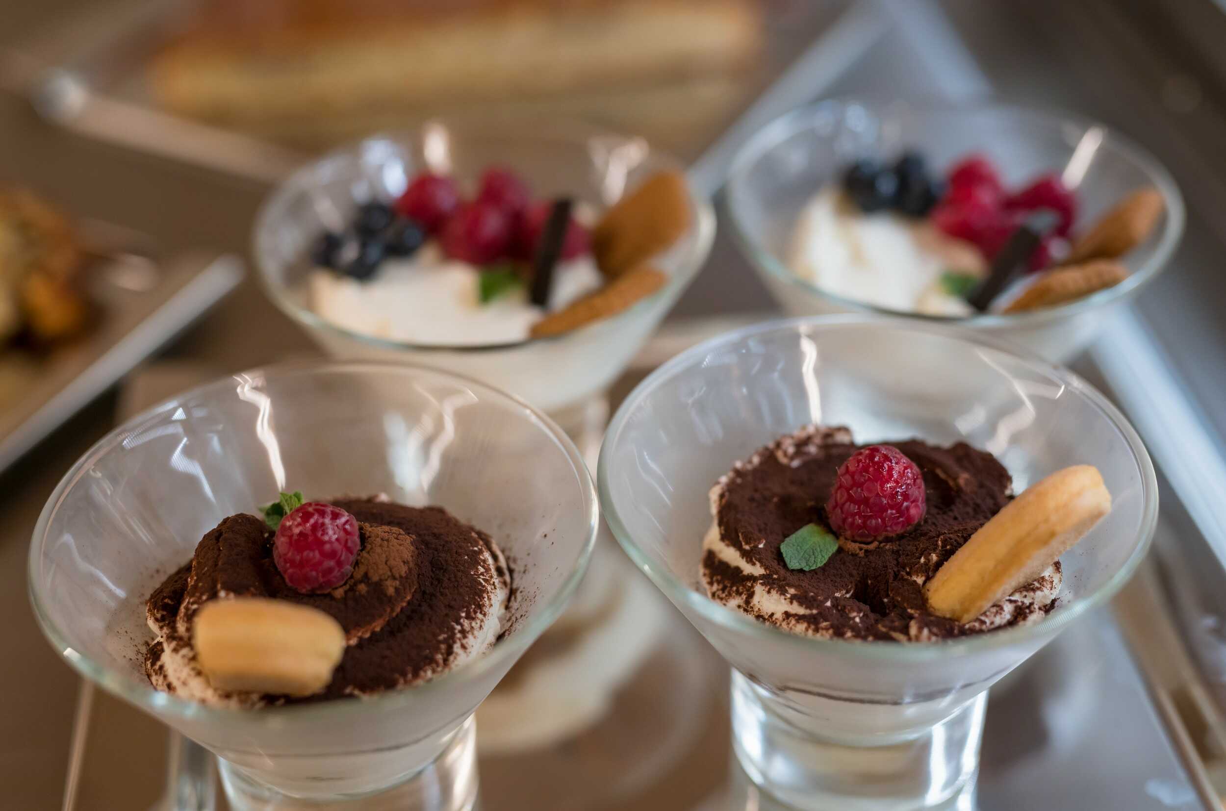 Domácí tiramisu v pohárech zdobené čerstvými malinami, borůvkami a cukrářskými piškoty.