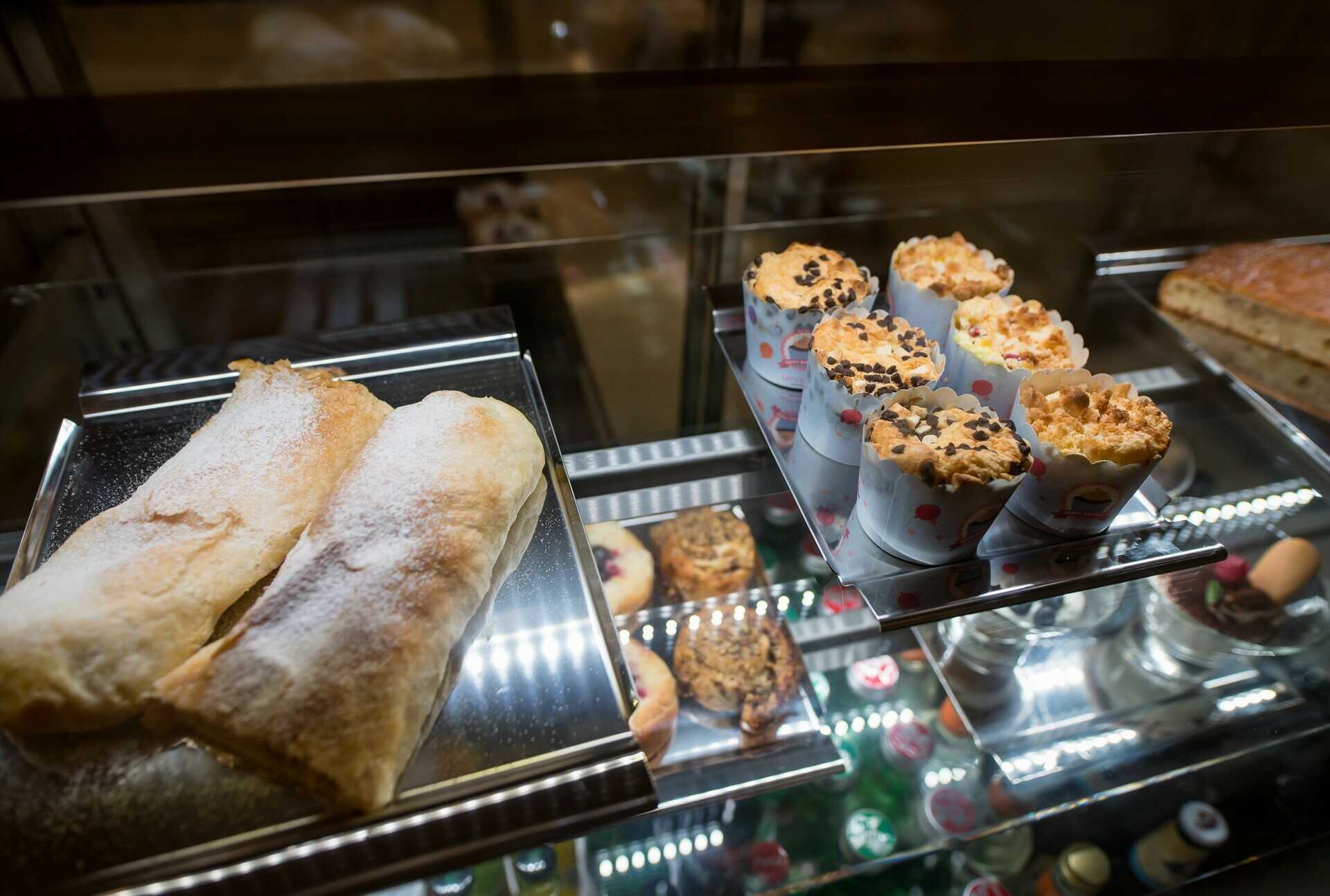 Pohled do prosklené vitríny s čerstvými domácími zákusky, sladkým pečivem a muffiny v třeboňské kavárně.