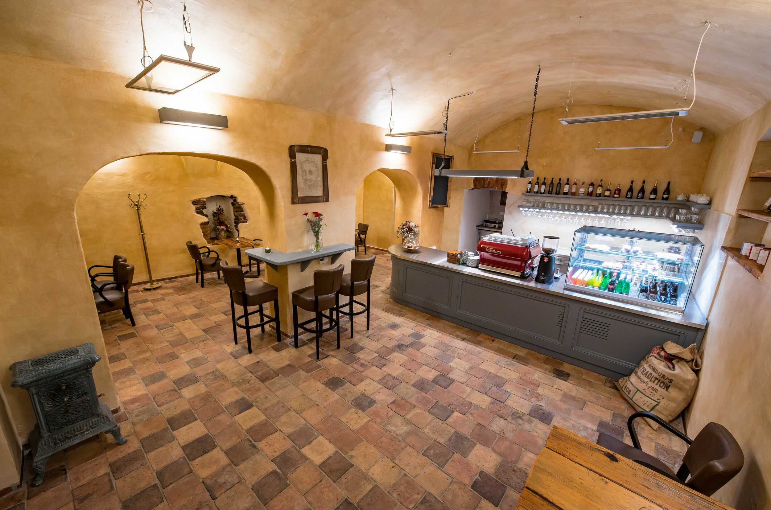 Útulná kavarná V Klenbách v Třeboni. Foto zachycuje interiér kavárny s historickými klenbami a tajemným obrysem muže v omítce, který je považován za ducha domu.