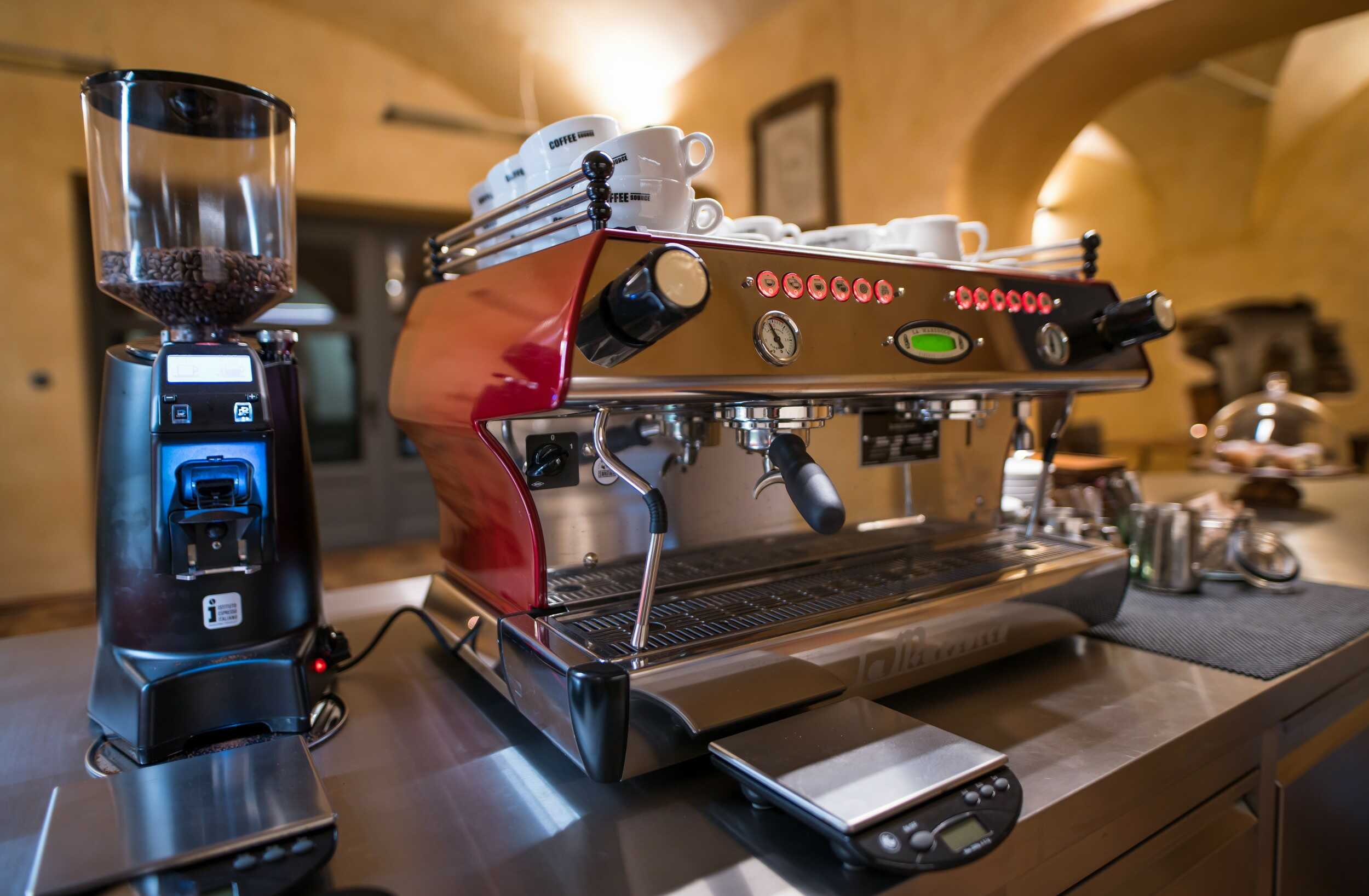 Profesionální červený kávovar La Marzocco na barovém pultu v historickém interiéru kavárny.