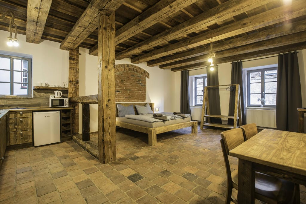 Pohled na velkorysý prostor Apartmánu 1 o rozloze 68 m² s masivními trámy a lůžky pro 4 osoby.