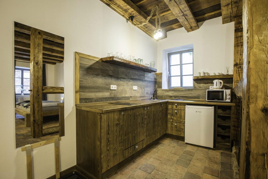 Plně vybavený kuchyňský kout v rustikálním stylu s lednicí a mikrovlnnou troubou v Apartmánu 1.