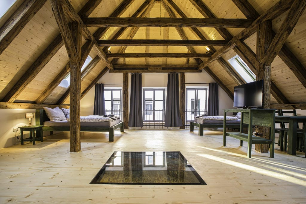 Prostorný podkrovní interiér o rozloze 65 m² s masivním dřevěným krovem a unikátním proskleným průhledem v podlaze.