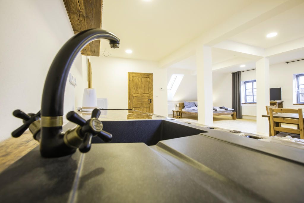 Detail designového černého dřezového kohoutku a pracovní desky v kuchyni Apartmánu 3.